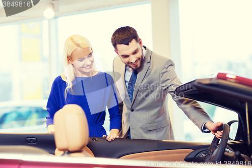 Image of happy couple buying car in auto show or salon