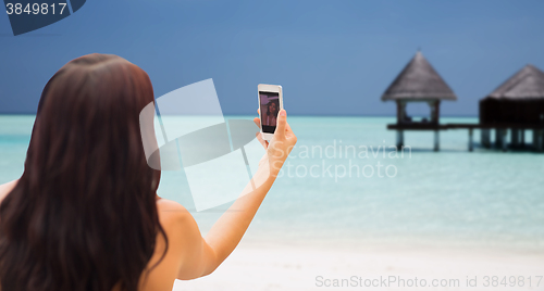 Image of young woman taking selfie with smartphone