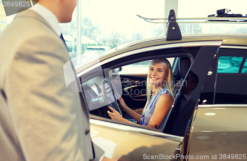 Image of happy woman with car dealer in auto show or salon