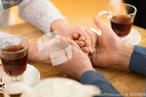 Image of close up of couple holding hands at restaurant