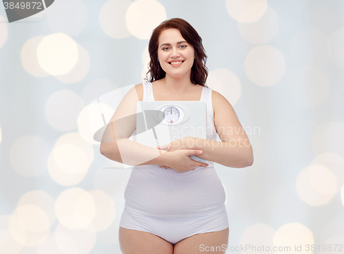 Image of happy young plus size woman holding scales