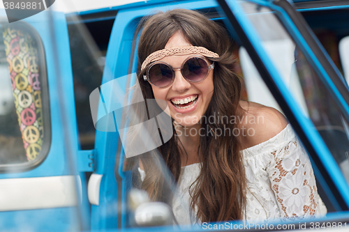 Image of smiling young hippie woman in minivan car