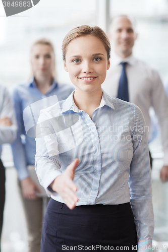 Image of smiling businesswoman making handshake in office