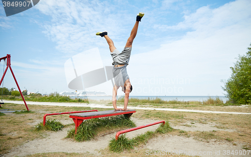 Image of young man exercising on bench outdoors