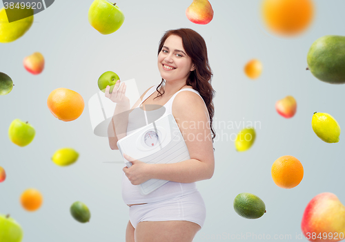 Image of happy young plus size woman holding scales