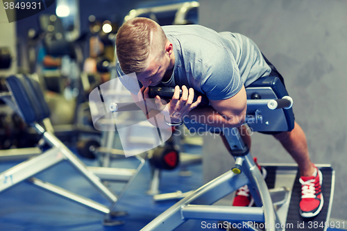 Image of young man flexing back muscles on bench in gym