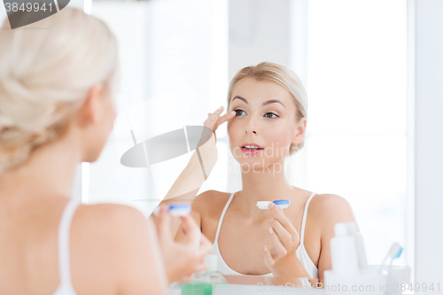 Image of young woman putting on contact lenses at bathroom