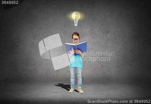 Image of happy little girl in eyeglasses reading book