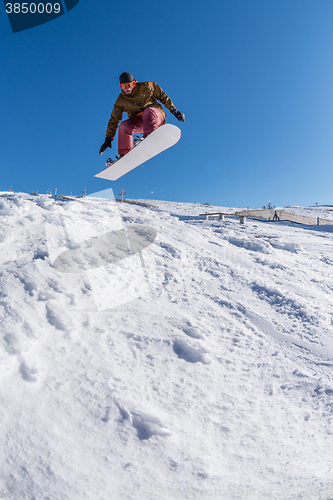 Image of Snowboarder jumping against blue sky