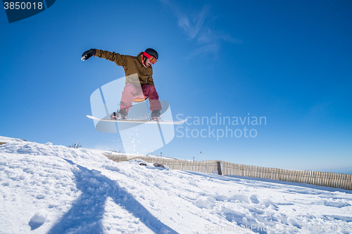 Image of Snowboarder jumping against blue sky