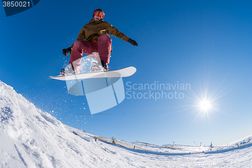 Image of Snowboarder jumping against blue sky