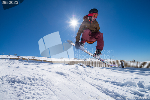 Image of Snowboarder jumping against blue sky