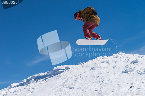 Image of Snowboarder jumping against blue sky