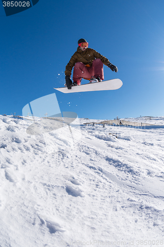 Image of Snowboarder jumping against blue sky