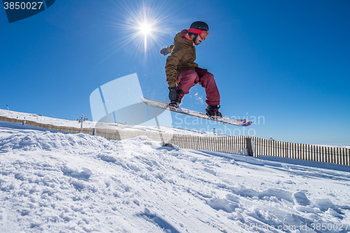 Image of Snowboarder jumping against blue sky