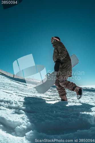 Image of Snowboarder walking against blue sky