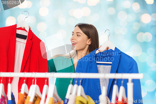 Image of happy woman choosing clothes at wardrobe