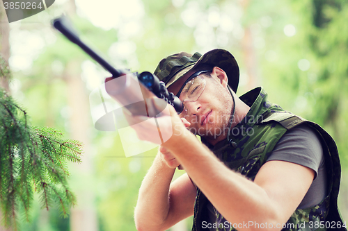 Image of young soldier or hunter with gun in forest