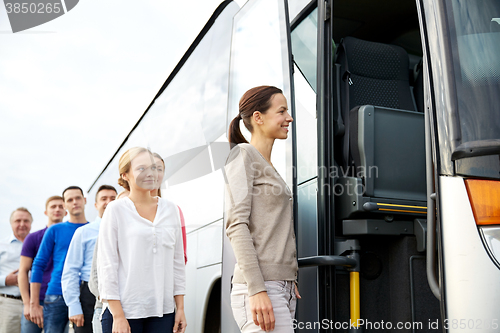 Image of group of happy passengers boarding travel bus