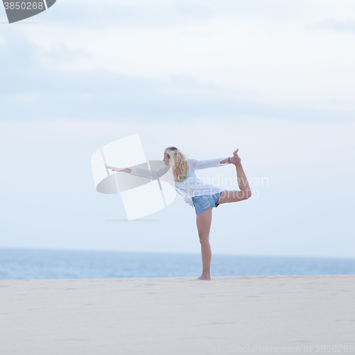 Image of Free woman streching on beach at down.