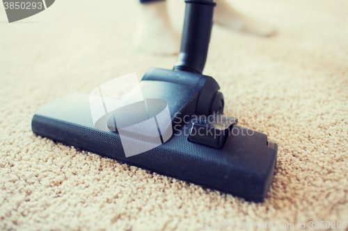 Image of close up of vacuum cleaner cleaning carpet at home