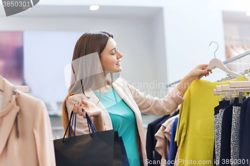 Image of happy young woman choosing clothes in mall