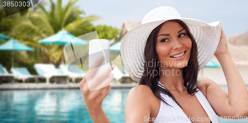 Image of young woman taking selfie with smartphone