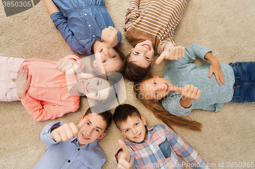 Image of happy children showing thumbs up on floor