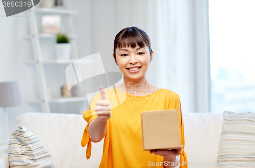 Image of happy asian young woman with parcel box at home