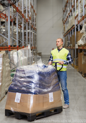 Image of man carrying loader with goods at warehouse