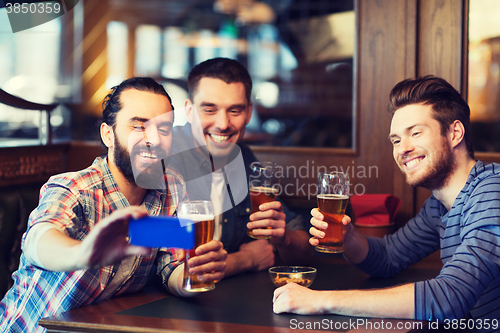 Image of male friends with smartphone drinking beer at bar