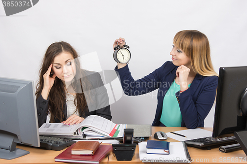 Image of  In the office at the end of the working day is one staff member would look at the clock and the other continues to work