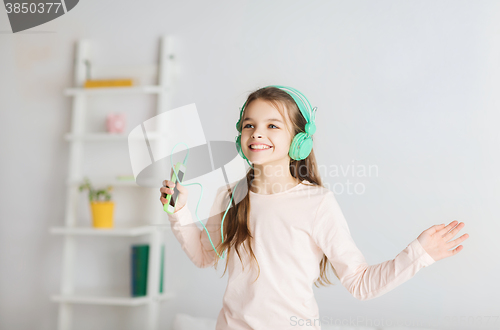 Image of girl jumping on bed with smartphone and headphones