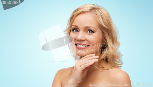 Image of smiling woman with bare shoulders touching face
