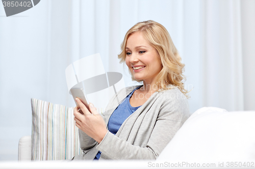 Image of smiling woman with smartphone texting at home