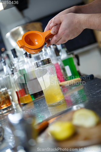 Image of Bartender is straining cocktail in a glass