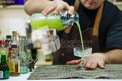 Image of barman pouring a pink cocktail drink 