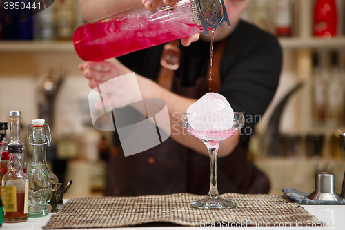 Image of barman pouring a pink cocktail drink 