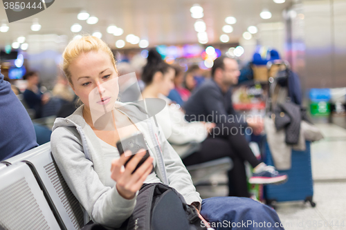 Image of Female traveler using cell phone while waiting.