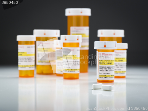 Image of Medicine Bottles and Pills on Reflective Surface With Grey Backg