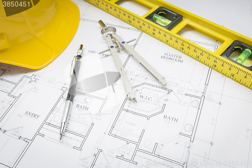 Image of Hard Hat, Pencil, Level and Compass Resting on House Plans