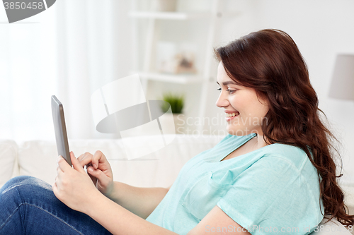 Image of happy young plus size woman with tablet pc at home