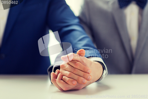 Image of close up of happy male gay couple holding hands