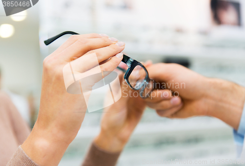 Image of close up of hands with glasses at optics store