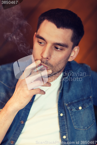 Image of young man smoking cigarette at bar