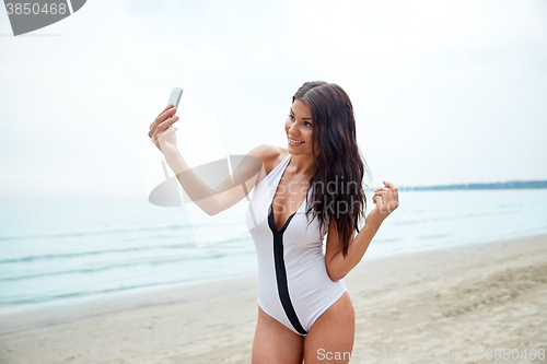 Image of young woman taking selfie with smartphone