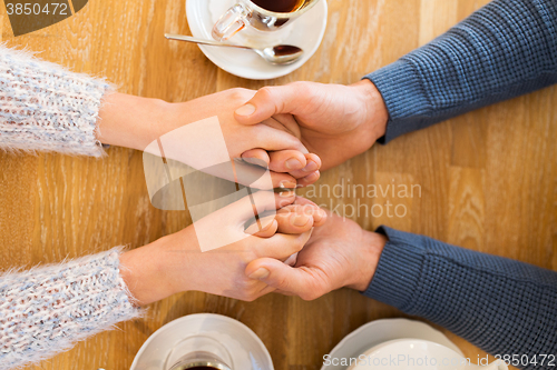 Image of close up of couple holding hands at restaurant