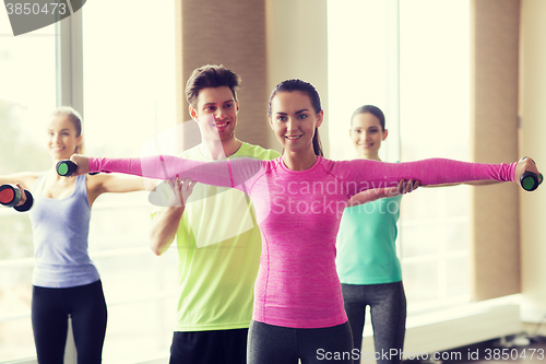 Image of happy women and trainer with dumbbells in gym