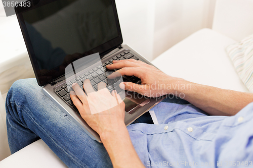 Image of close up of man typing on laptop computer at home