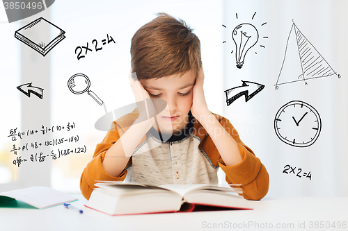 Image of student boy reading book or textbook at home